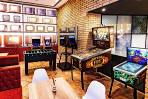 Une pièce équipée d’un baby-foot, d’un tapis de course et de divers jeux d’arcade.