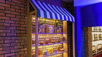 A brick wall with a striped awning and shelves displaying various fruits and bottles.