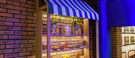 A brick wall with a striped awning and shelves displaying various fruits and bottles.