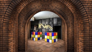 Un intérieur caractérisé par des arches en briques, un néon et deux tables de forme cubique.