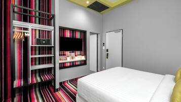 A hotel room with a bed, a wardrobe, a television, and a shelf with items.