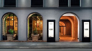 Un bâtiment doté de trois entrées en arc de cercle, chacune étant surmontée d’une enseigne indiquant « MAMAISON VIBE ».