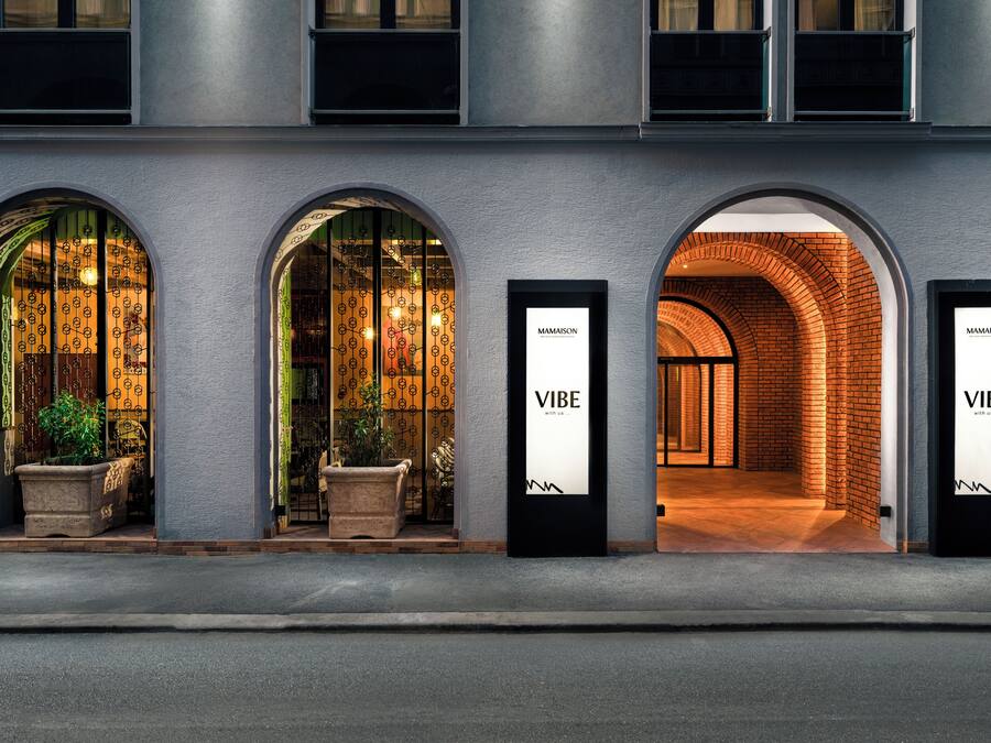 A building with three arched entrances, each with a sign reading 'MAMAISON VIBE.'