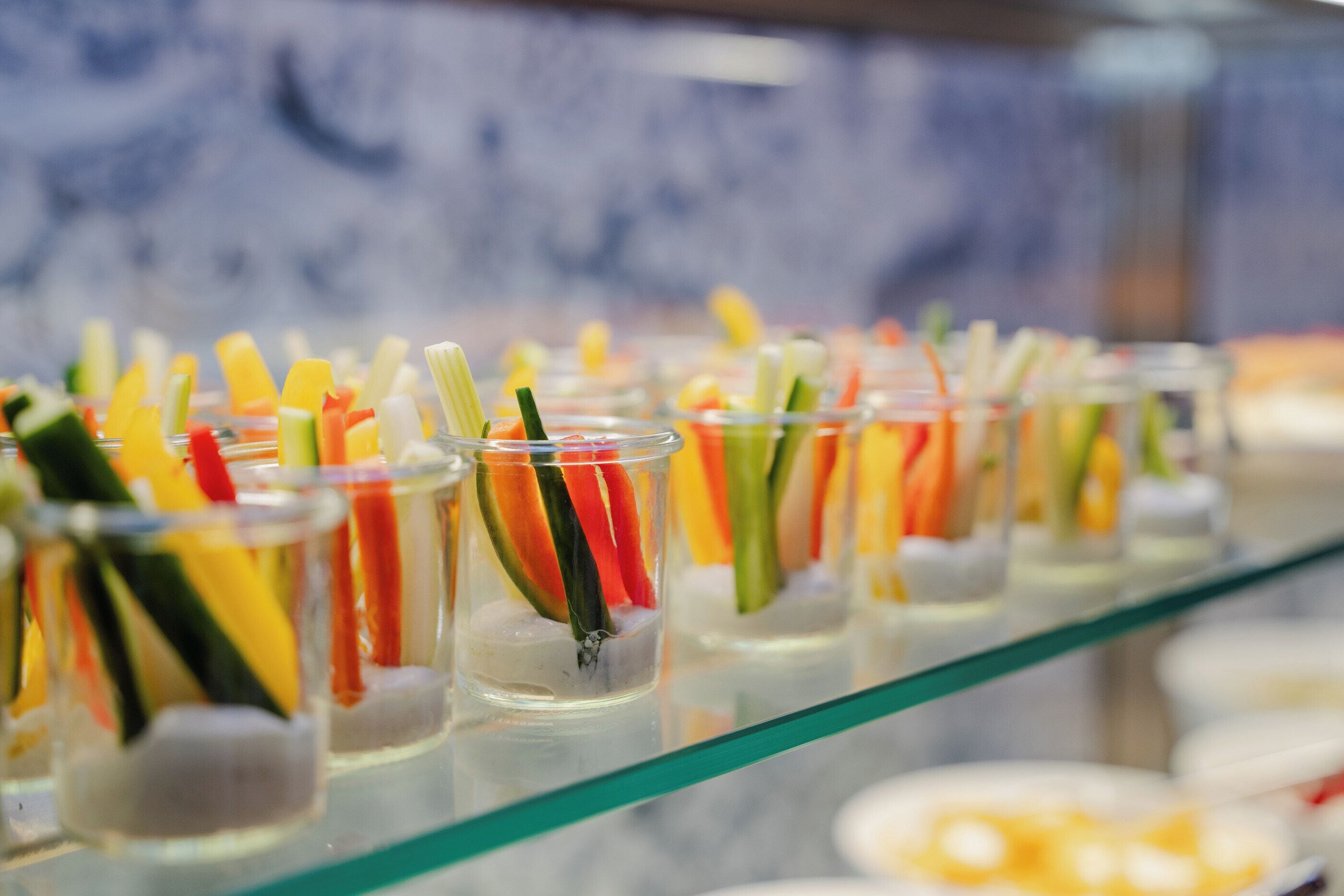 A buffet with various food items in clear glasses.