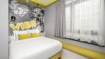 Een moderne slaapkamer met een bed, een hoofdbord, een nachtkastje en een raam met dunne gordijnen.