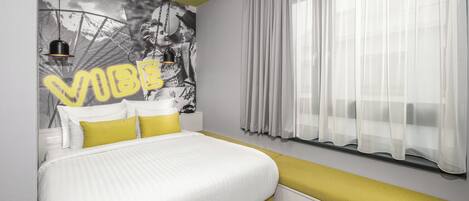 Un dormitorio moderno con cama, cabecera, mesita de noche y ventana con cortinas de gasa.