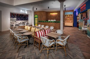 Um restaurante com cadeiras de vime, mesas de madeira e almofadas listradas.