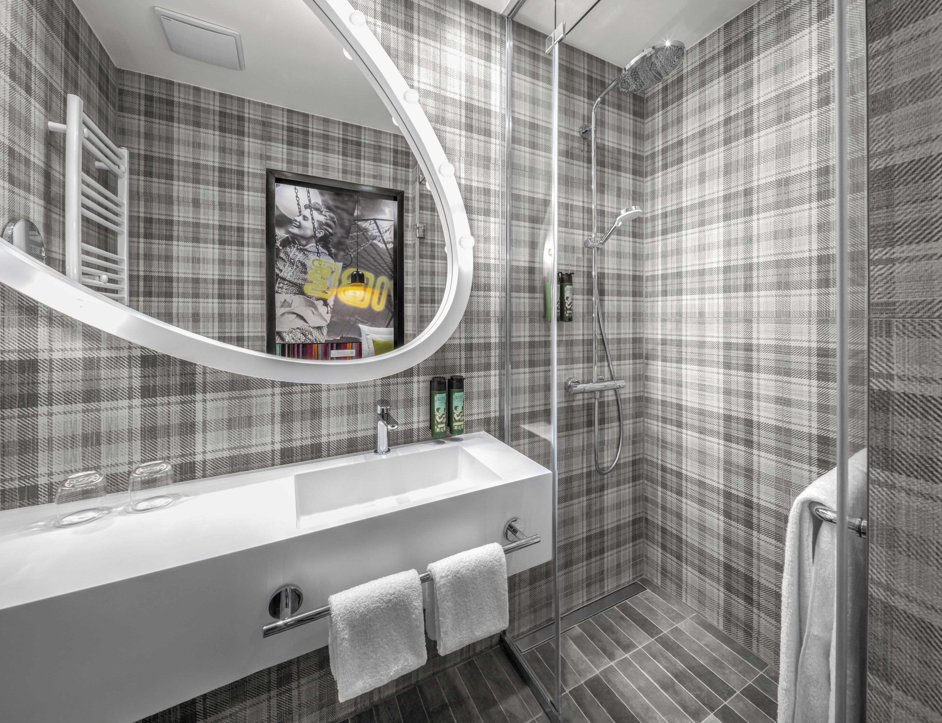 A modern bathroom with a large mirror, a shower, and a sink.