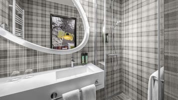 A modern bathroom with a large mirror, a shower, and a sink.