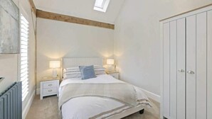 Ein Schlafzimmer mit Bett, Nachttischen, einem Kleiderschrank und einem Oberlicht.