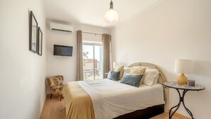 Un dormitorio con cama, una silla, una mesa y un televisor.