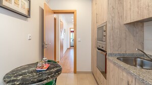 Cocina con encimera de mármol, armarios de madera y pileta de acero inoxidable.