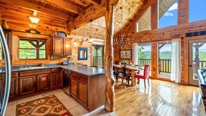 A spacious kitchen with wooden cabinets, a large island, and a dining area with a view. - Mountain Views • Hot Tub • Minutes to Dollywood (Sevierville)