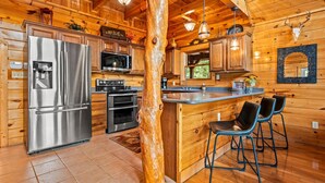 A wooden cabin kitchen with a stainless steel refrigerator, microwave, and oven. - Mountain Views • Hot Tub • Minutes to Dollywood (Sevierville)