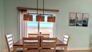 Comedor con mesa y sillas, vista a través de una ventana y una lámpara fijada a la pared.