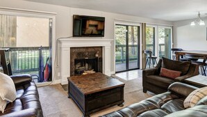 Una sala de estar con chimenea, sofás de cuero, una mesa de centro y un televisor.