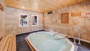 Habitación de spa con techo de madera, bañera de hidromasaje y cartel que indica prohibido fumar y el uso de vidrio.