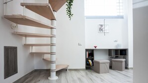A modern interior with a spiral wooden staircase, a bookshelf, and a small seating area. - Solarium al Duomo Rooms by Wonderful Italy (Naples)