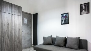 A room with a grey sofa, a wooden wardrobe, and two framed pictures on the wall. - Solarium al Duomo Rooms by Wonderful Italy (Naples)