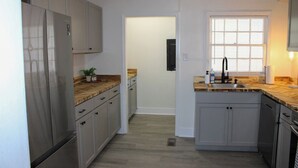 A kitchen with light wood cabinets, a stainless steel refrigerator, a wooden countertop, and a window with blinds. - Corner Cottage - 2BR, Close to Lake, Restaurants! (Spring City)