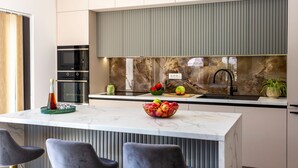A modern kitchen with a marble countertop, a built-in oven, and a backsplash with a stone-like texture. - Vila SUNLIFE with pool&sauna by Villas Guide (Matulji)
