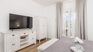 Een hotelkamer met een bed, een televisie op een witte kast, een kledingkast en uitzicht op het omliggende landschap.