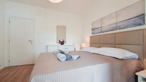 Une chambre à coucher avec un lit, une commode, un miroir et un tableau accroché au mur.