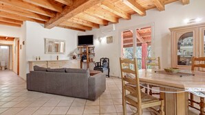 Ein Wohnzimmer mit einer Couch, einem Holzesstisch, Stühlen und einem Fernseher.
