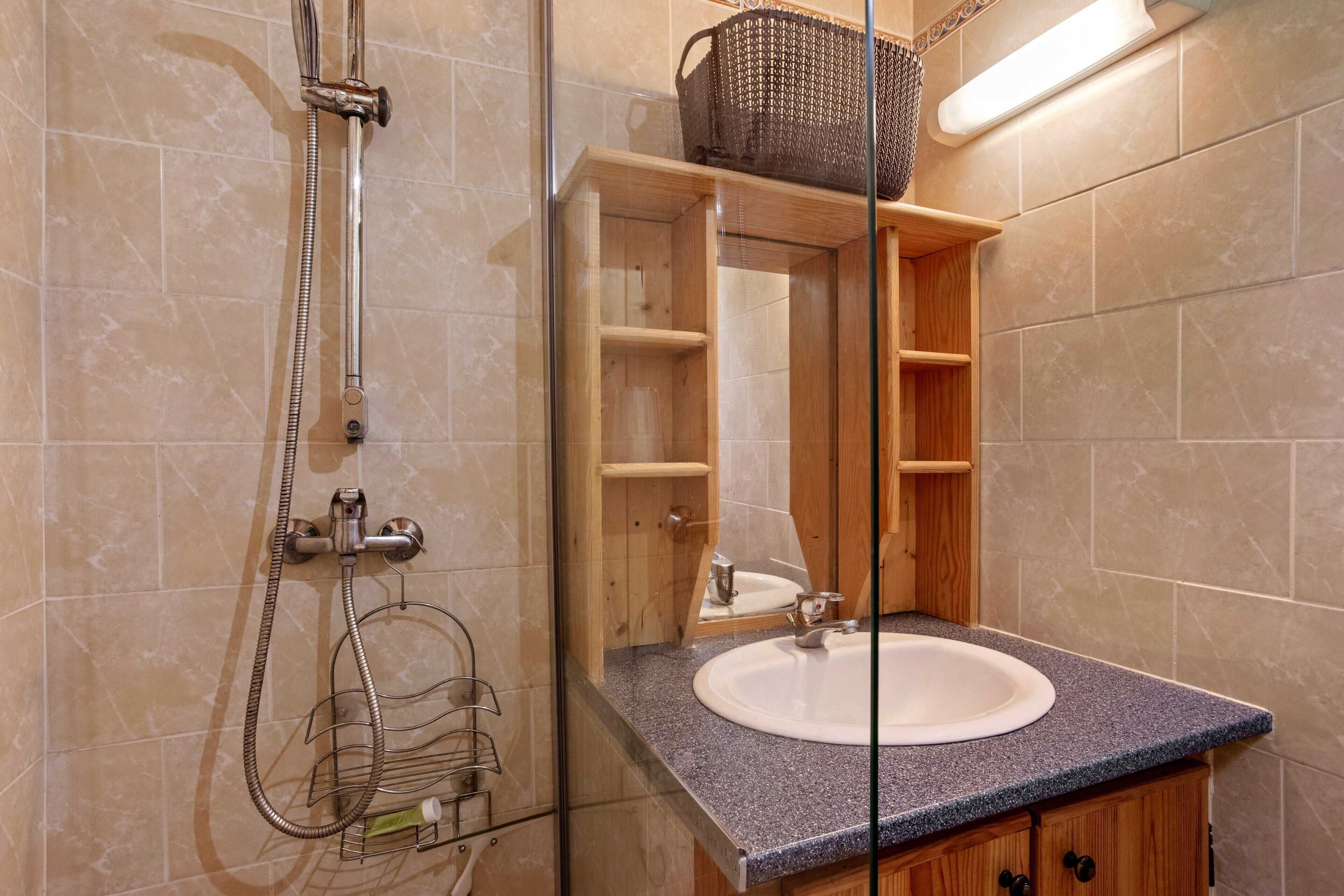 Une salle de bain avec une douche, un lavabo et un meuble en bois.