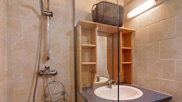 Une salle de bain avec une douche, un lavabo et un meuble en bois.