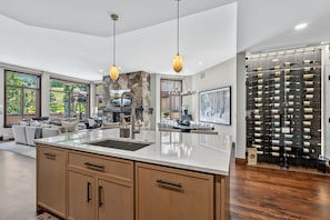 A modern kitchen with a large island, stone accent wall, and a wine rack.