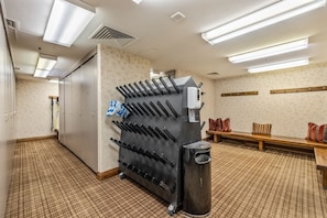 A hotel room with a large black appliance, possibly a coffee machine, a bench with pillows, and a trash can.