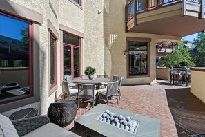 Un patio con una mesa redonda y sillas, una planta en maceta y un elemento decorativo de piedra.
