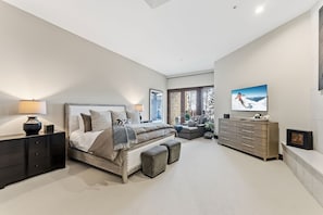A modern bedroom with a bed, bedside tables, a dresser, and a television.