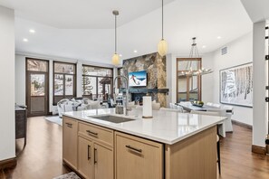 Une cuisine moderne dotée d’un grand îlot central, d’un mur d’accent en pierre et d’une cheminée.