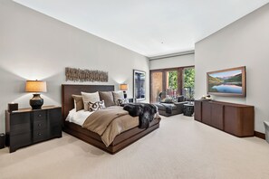 Un dormitorio con una cama grande, mesitas de noche, un aparador y un cuadro en la pared.