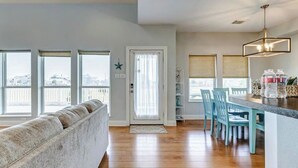 A spacious living area with a sofa, a dining table with chairs, and a kitchen area with a chandelier.