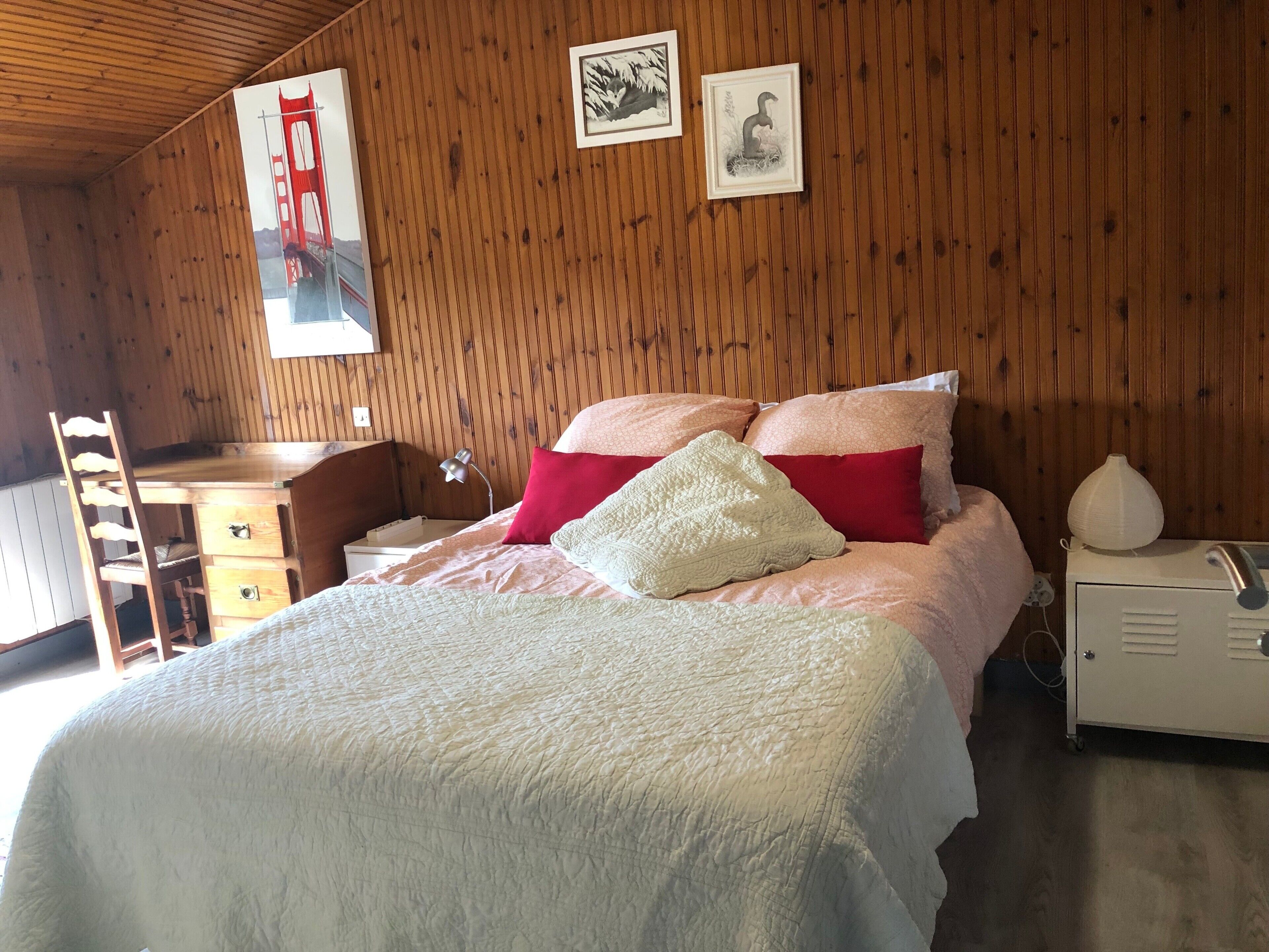 Ein Zimmer mit Holzwänden, einem Bett, einem Schreibtisch und einem Stuhl.