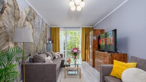 A modern living room with a sofa, a coffee table, a TV, and a large window with curtains.