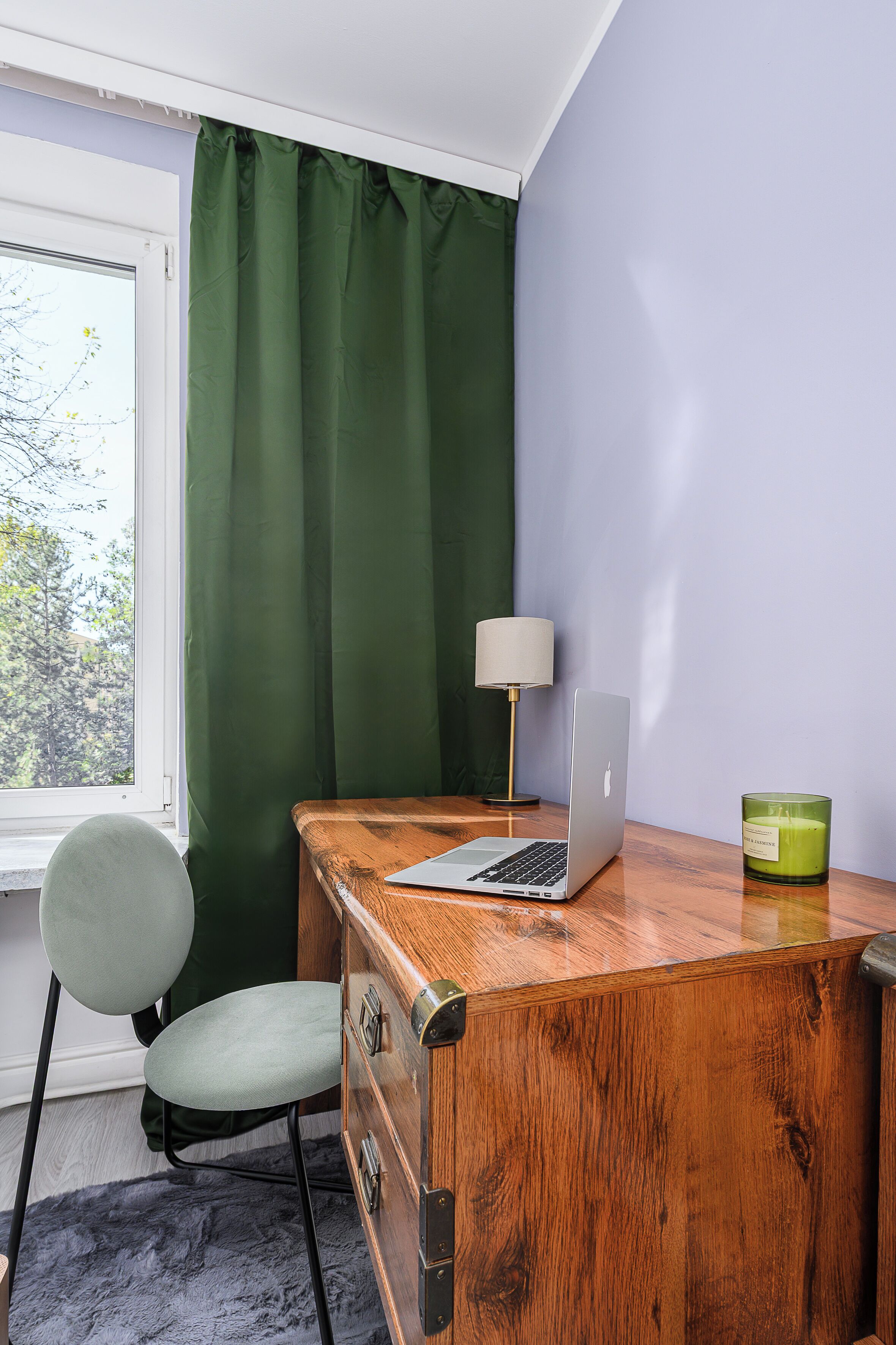 Et træskrivebord med en bærbar computer, et grønt lys og en lampe.