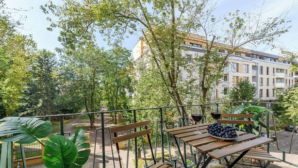 A balcony with wooden furniture, a bowl of fruit, and a wine glass.