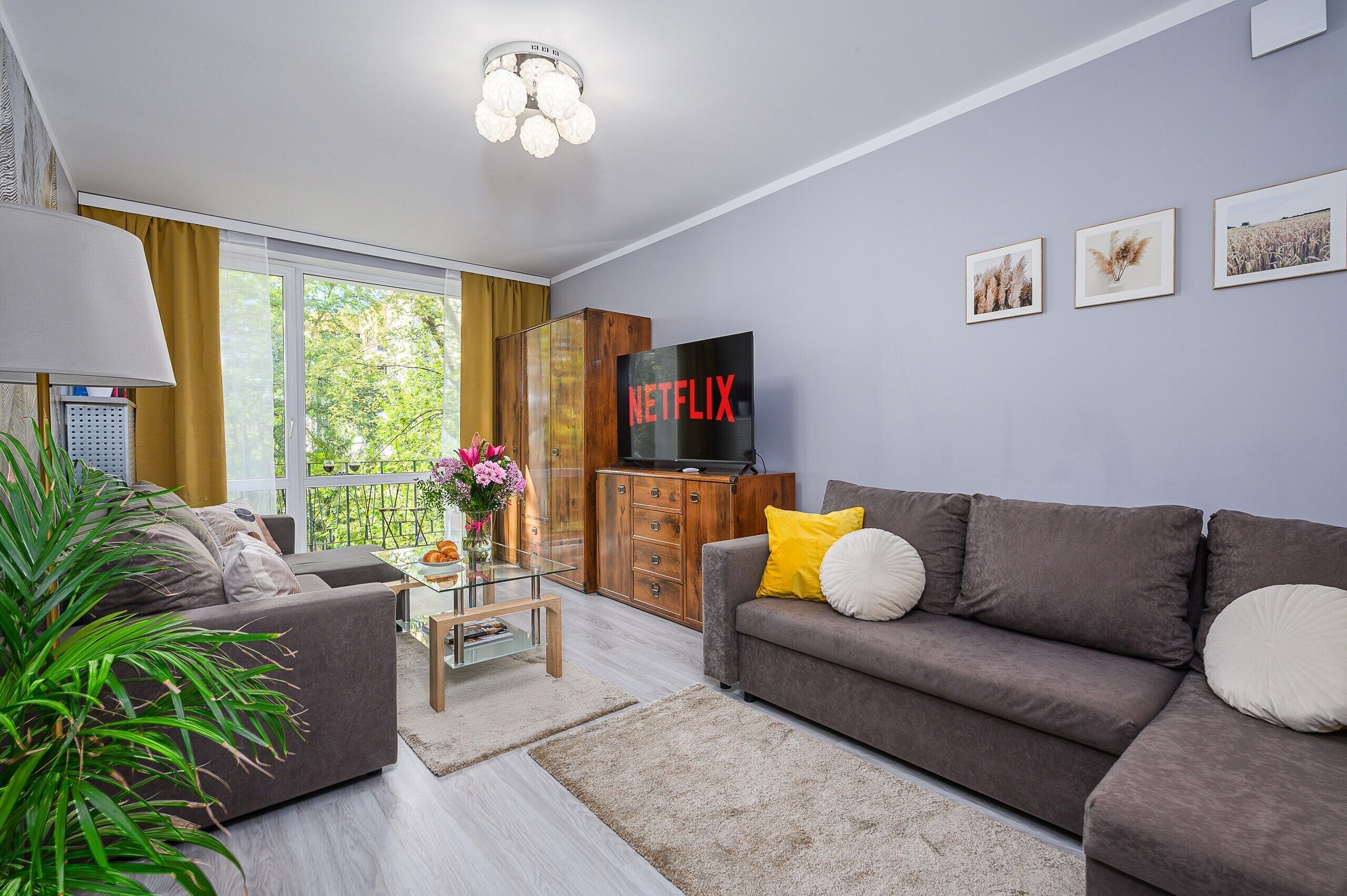A modern living room with a grey sofa, a coffee table, and a TV mounted on a wooden cabinet.