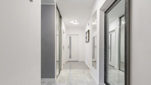 A hallway with a tiled floor, white walls, and large mirrors on both sides.