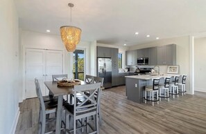 A modern kitchen with grey cabinets, stainless steel appliances, and a central island with bar stools. - New Rental on St. George with HEATED PRIVATE POOL! Beach Gear Provided,    Pets👍🏻 (Saint George Island)