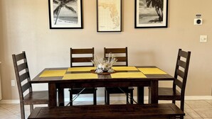 A dining area with a table set for four, framed pictures on the wall, and a sign that reads 'PARADISE'. - Waterfront Playground in Paradise - more than a condo rental, a destination! (Destin)