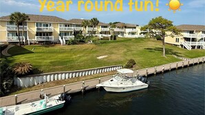 A waterfront hotel with multiple balconies, a grassy lawn, and boats docked at the pier. - Waterfront Playground in Paradise - more than a condo rental, a destination! (Destin)