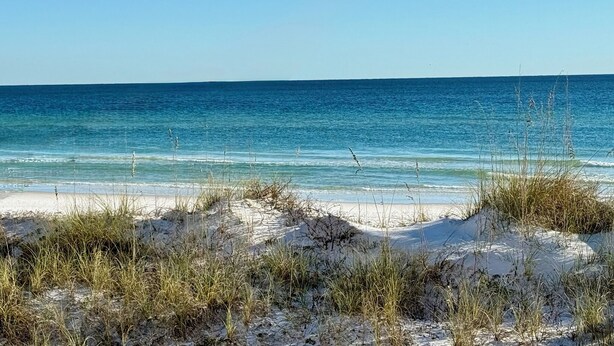 A beach with clear blue water and sand dunes. - Waterfront Playground in Paradise - more than a condo rental, a destination! (Destin)