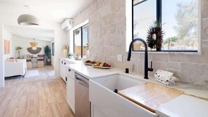 Une cuisine moderne dotée d’une grande fenêtre, d’un lave-vaisselle encastré et d’un plan de travail en bois.