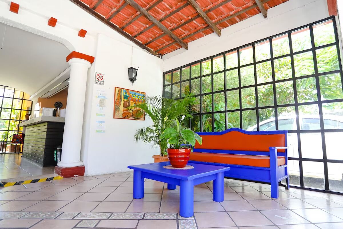 A lobby with a blue and orange bench, a tiled floor, and a large window with greenery outside.