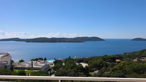 Blick auf die Küste mit blauem Himmel, einem Schwimmbecken und einer fernen Insel.
